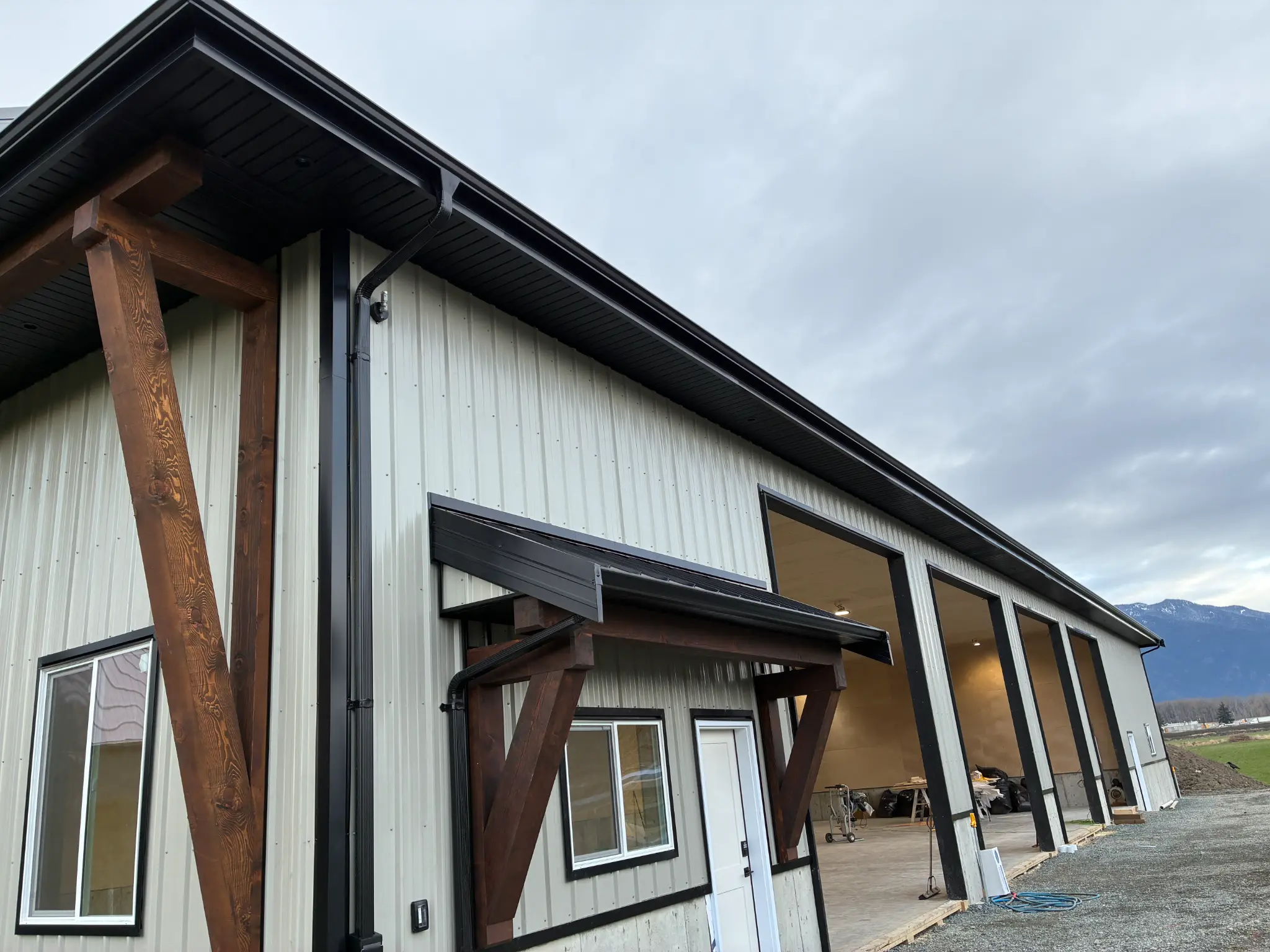 Seamless black gutter and fascia installation on commercial metal building