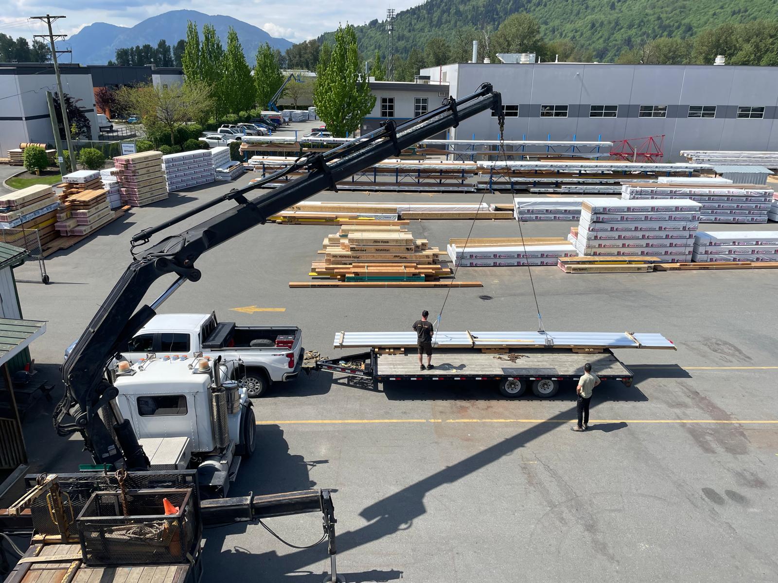 Crane loading metal panels onto flatbed trailer